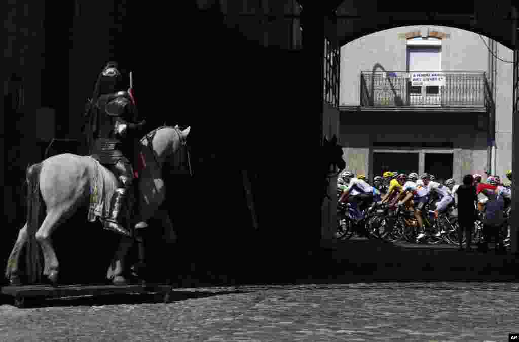 The pack with Britain's Geraint Thomas, wearing the overall leader's yellow jersey rides past a Horse statue during the sixteenth stage of the Tour de France cycling race.