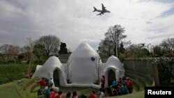 Anak-anak di sekolah pendidikan dini Hounslow Heath di London mengelilingi salah satu dari empat bangunan berkubah di sekolah mereka yang dibangun untuk meredam suara pesawat. (Reuters/Stefan Wermuth)