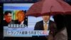 FILE - A woman walks past a public TV screen showing North Korean leader Kim Jong Un, left, and U.S. President Donald Trump, right, in Tokyo, March 9, 2018. The signs reads: "Trump has accepted an offer of a summit from the North Korean leader and will meet with Kim by May."