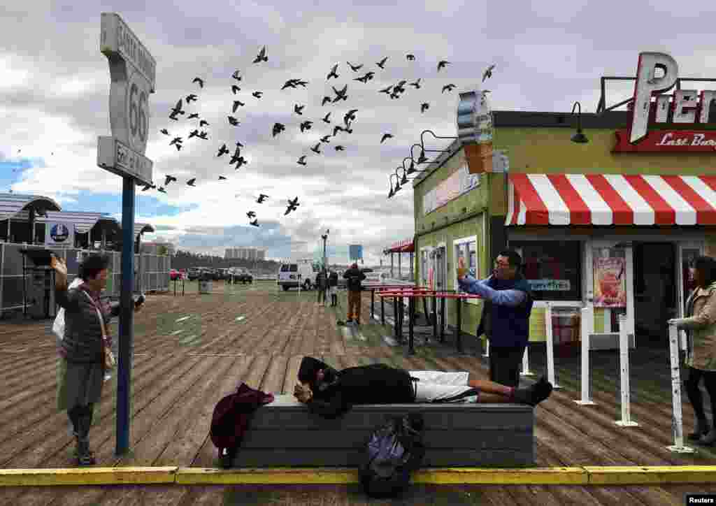 A man takes a photo of a woman at Santa Monica Pier in Santa Monica, Los Angeles, Nov. 21, 2016.