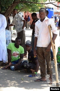 These young men say that polio not only robbed them of the use of their legs, but of their ability to work for a living. They say they beg for money in this Abuja market for food and school fees. (VOA/H. Murdock)