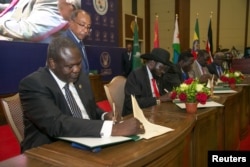 South Sudanese rebel leader Riek Machar, left, and South Sudan's President Salva Kiir sign a ceasefire and power sharing agreement in Khartoum, Sudan, Aug. 5, 2018.