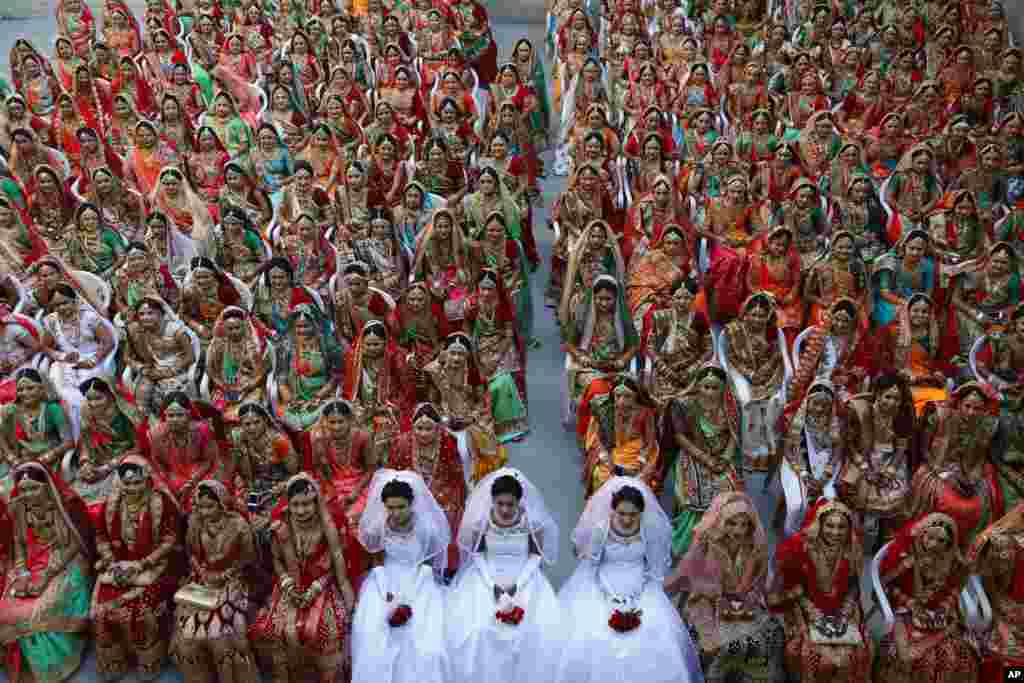 Indian brides sit together for a group photograph during a mass wedding in Surat.