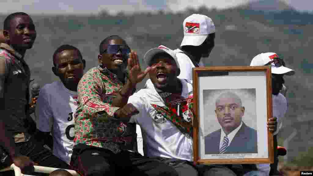 Des partisans du président du Burundi, Pierre Nkurunziza, jonchés sur un véhicule avec son effugie en mains, attendent le passage de son convoi dans la capitale, dans une rue à Bujumbura, après un coup d&#39;Etat manqué au Burundi, le 15 mai 2015.
