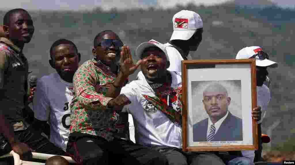 Des partisans du président du Burundi, Pierre Nkurunziza, jonchés sur un véhicule avec son effugie en mains, attendent le passage de son convoi dans la capitale, dans une rue à Bujumbura, après un coup d&#39;Etat manqué au Burundi, le 15 mai 2015.