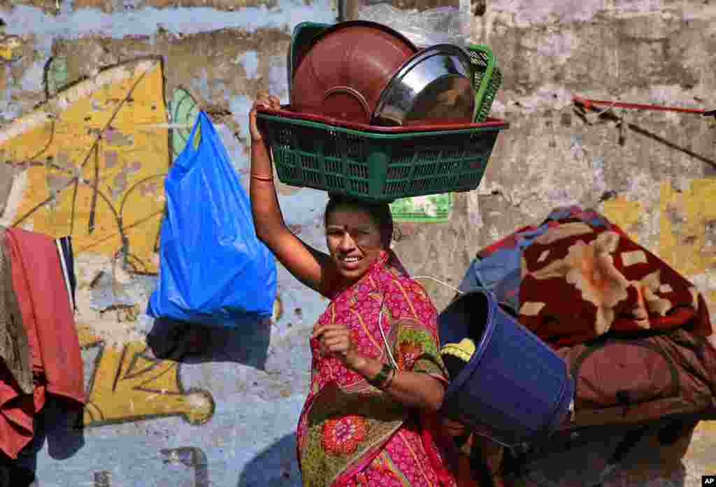 An Indian woman walks carrying utensils for sale on International Women's Day in Mumbai, India, March 8, 2015.