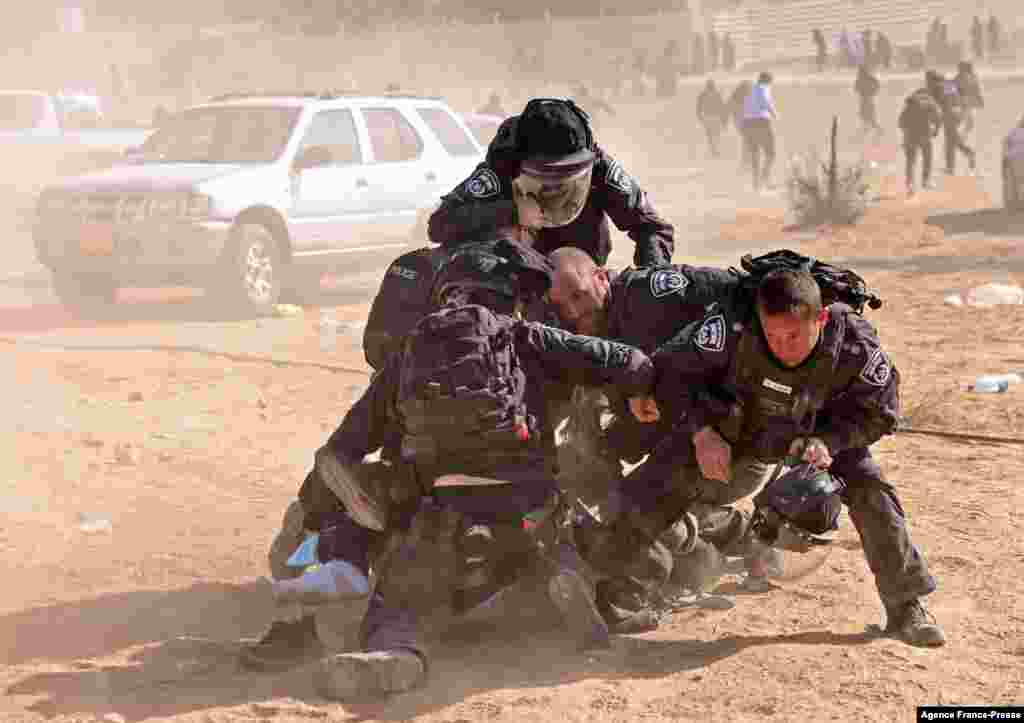 Lima polisi Israel menahan seorang pria Arab Badui saat warga Badui memprotes proyek penghijauan oleh Dana Nasional Yahudi (JNF), di desa Sa&#39;we al-Atrash, Gurun Neguev,&nbsp;Israel selatan Rabu (12/1). (Foto: AFP)