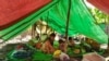 This photo taken and received courtesy of an anonymous source on May 7, 2021 shows villagers from King village sitting under a shelter in the open after they fled fighting that broke out between fellow villagers and the Myanmar military in Kani township, 