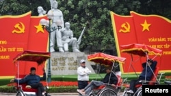Những người lái xích lô chờ khách bên các tấm áp phích của Đại hội 13 của Đảng Cộng sản khai mạc hôm 25/1 tại Hà Nội.