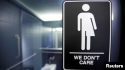 FILE -- A sign protesting a recent North Carolina law restricting transgender bathroom access is seen in the bathroom stalls at the 21C Museum Hotel in Durham, North Carolina May 3, 2016. 