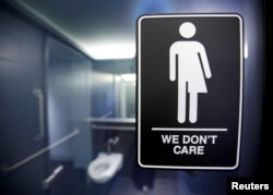 FILE -- A sign protesting a recent North Carolina law restricting transgender bathroom access is seen in the bathroom stalls at the 21C Museum Hotel in Durham, North Carolina May 3, 2016.