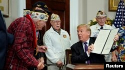 El presidente Donald Trump muestra a uno de los veteranos de Pearl Harbor, Lawrence Parry, la proclamación firmada y dijo que entregaría a los veteranos lapiceros para recordar el momento.