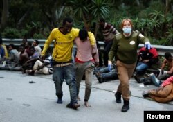 African migrants help each other as they arrive at the CETI, the short-stay immigrant centre, after crossing the border from Morocco to Spain's North African enclave of Ceuta, Spain, Feb. 17, 2017.