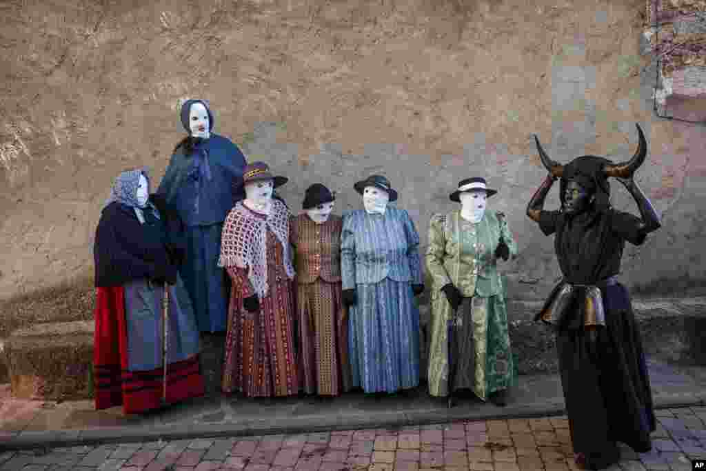 A reveler, dressed as &quot;Diablos de Luzon&quot; or Luzon Devil&#39;s, covered in oil and soot carrying bull horns on his head and cowbells on a belt representing the devil, and others dressed as &quot;Mascaritas&quot; take part in the carnival celebration in the small village of Luzon, Spain, Feb. 25, 2017.