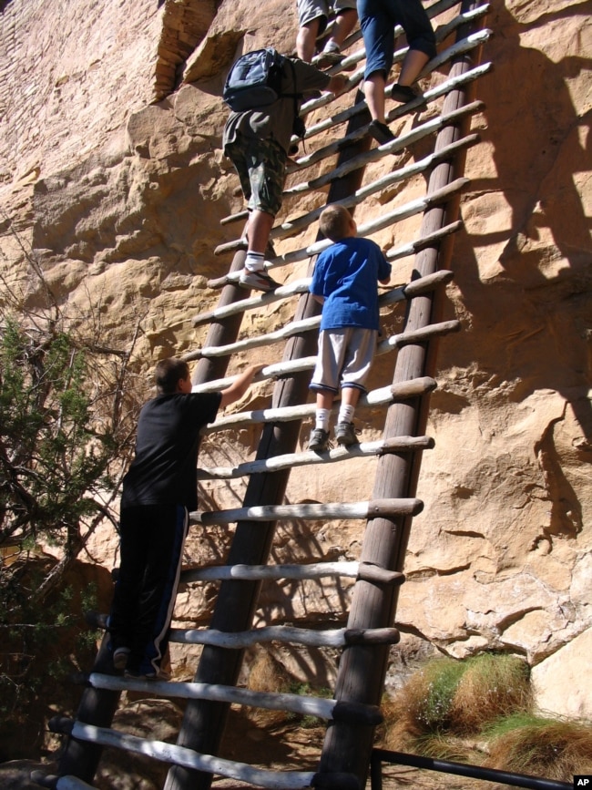 Visitors climb steep ladders on a tour of Balcony House, an ancient cliff dwelling in Mesa Verde National Park