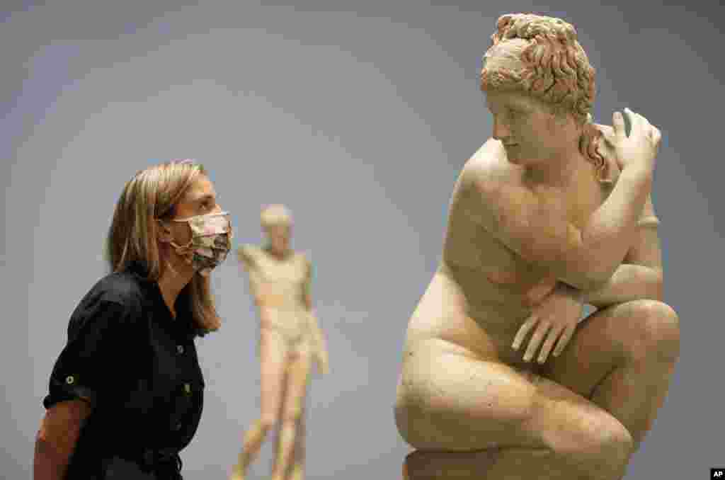 A museum employee looks toward a marble statue of Crouching Venus, Roman, 2nd century AD, during a press view at The British Museum in London.