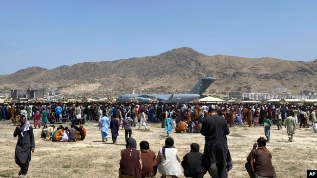 Njerëzit e mbledhur përreth një aeroplani transportues në aeroportin e Kabulit