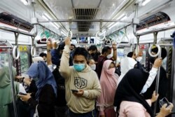 Penumpang yang memakai masker berdiri di dalam kereta komuter pada jam sibuk di sore hari saat varian omicron terus menyebar di Jakarta, 3 Januari 2022. (Foto: REUTERS/Willy Kurniawan)