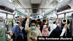 Penumpang mengenakan masker, berdiri di dalam kereta komuter pada jam sibuk sore hari di tengah merebaknya varian omicron di Jakarta, 3 Januari 2022. (REUTERS/Willy Kurniawan)