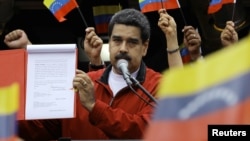 FILE - Venezuela's President Nicolas Maduro shows a document with the details of a "constituent assembly" to reform the constitution during a rally at Miraflores Palace in Caracas, Venezuela, May 23, 2017.