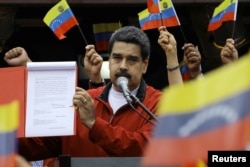 FILE - Venezuela's President Nicolas Maduro shows a document with the details of a "constituent assembly" to reform the constitution during a rally at Miraflores Palace in Caracas, Venezuela, May 23, 2017.