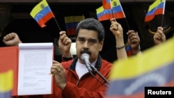Venezuela's President Nicolas Maduro shows a document with the details of a "constituent assembly" to reform the constitution during a rally at Miraflores Palace in Caracas, Venezuela, May 23, 2017.