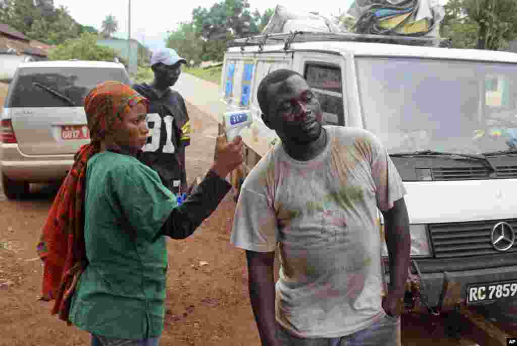 A health worker uses a thermometer to screen a man&#39;s temperature at a makeshift road block run by Guinean security forces near the town of Forecariah, Guinea, Sept. 7, 2014.&nbsp;