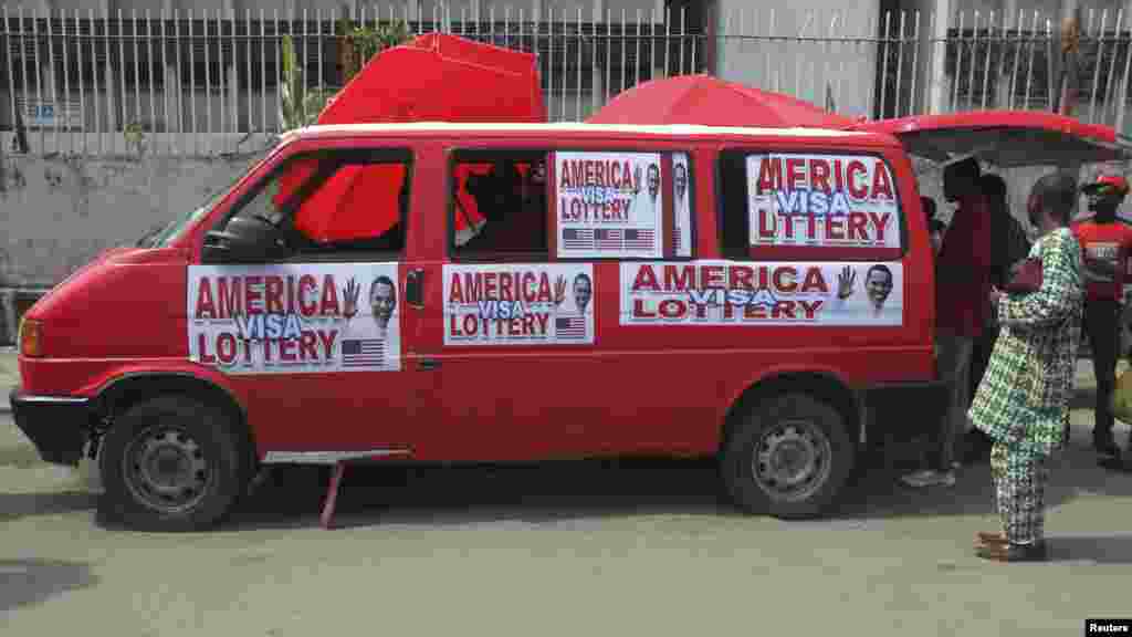 A bus advertising an American visa lottery is parked along a street in Lagos.