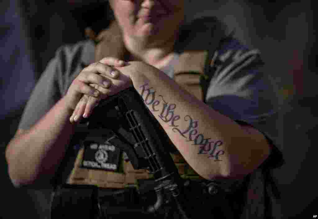 The tattoo "We The People", a phrase from the United States Constitution, decorates the arm of Trump supporter Michelle Gregoire as she rests her hand on her gun during a protest over the election results outside the central counting board at the TFC Cent