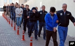 FILE - Police officers escort people arrested because of suspected links to U.S.-based cleric Fethullah Gulen — blamed by Ankara for the failed coup — in Kayseri, Turkey, April 26, 2017.