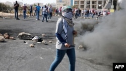 Palestinian protesters hurl stones towards Israeli security forces during clashes near the Beit El settlement on the outskirts of Ramallah in the West Bank, Oct. 17, 2015.