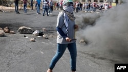 约旦河西岸拉马拉郊外的巴勒斯坦抗议者在冲突中向以色列保安部队投掷石块。（2015年10月17日）