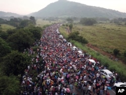 FILE - Members of a US-bound migrant caravan stand on a road after federal police briefly blocked their way outside the town of Arriaga, Saturday, Oct. 27, 2018.