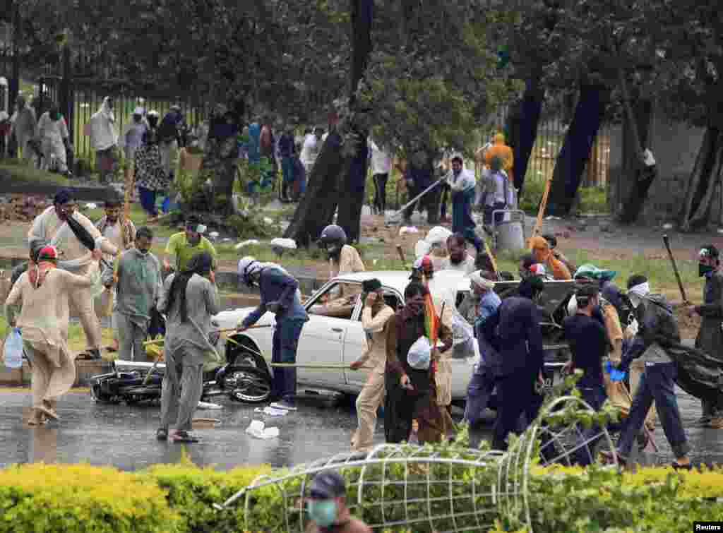 Demonstrators use sticks to hit a car and a motorcycle as they protest, Islamabad, Sept. 1, 2014.