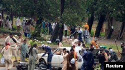 Manifestan sèvi ak baton pou yo frape yon machin ak yon motosiklèt pandan yo tap defile nan sa yo rele "Mach Revolisyon an" nan direksyon kay premye minis Nawaz Sharif. (Foto: Islamabad, premye septanm 2014).