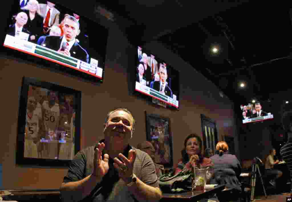 Frank Nieves, of the Puerto Rican/Hispanic Chamber of Commerce, a supporter of President Barack Obama applauds as he watches a televised debate between Republican presidential candidate Mitt Romney, and Mr. Obama, Miramar, Florida.