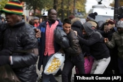 Migrants run to board buses to temporary shelters in Paris, Friday, Nov. 4, 2016.