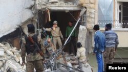 Warga dan tentara pemberontak Suriah memeriksa kerusakan pasca serangan udara Rusia di kota Idlib, Suriah Minggu (20/12).
