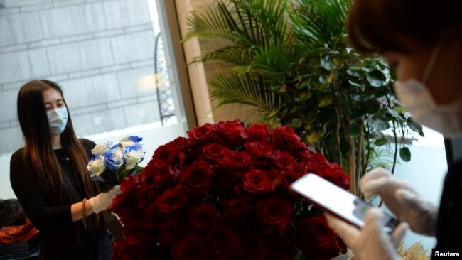 北京金融中心一家花店的工作人员带着口罩为情人节的花束订购做准备。（2020年2月14日路透社资料照）