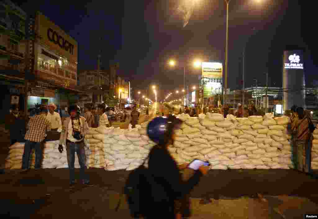 Anti-government protesters wait behind a barricade after closing the road near Government Complex, Bangkok Jan. 12, 2014.