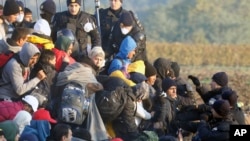 Migrants enter Croatia from Serbia as Croatian police officers stand guard the fence at a border between Serbia and Croatia, near the village of Babska, Croatia, Oct. 21, 2015. 