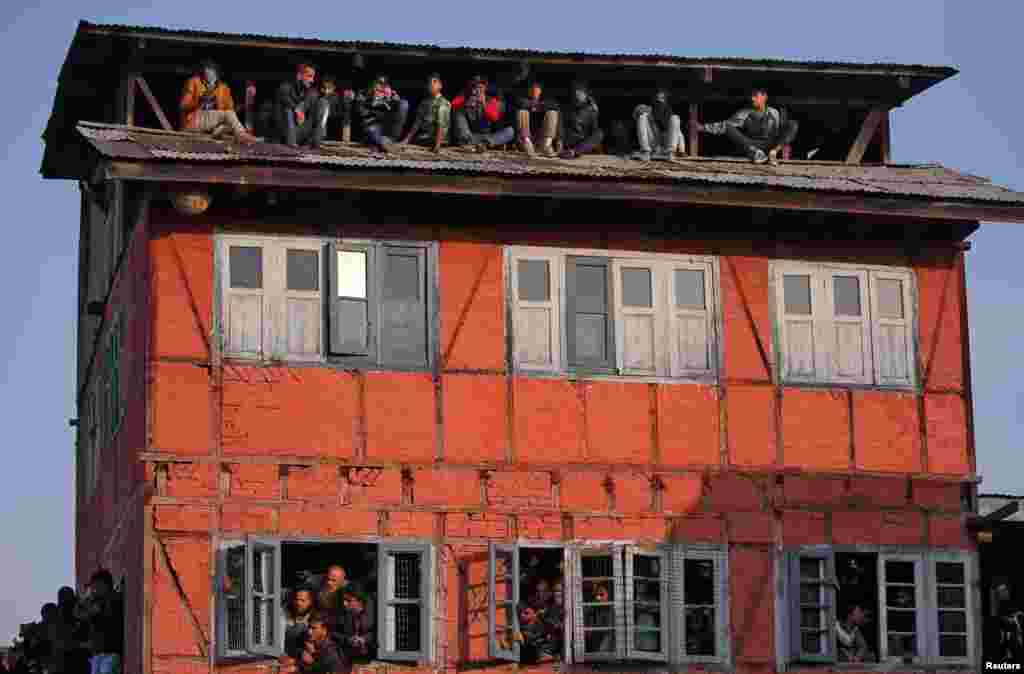 People watch the body of Mehraj-ud-Din Bangroo, a suspected militant, who according to local media was killed in a gunbattle with Indian security forces, from a residential house during his funeral procession in Srinagar.