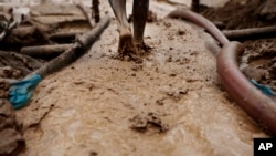 A man walks on special carpets that are used to filter earth and water in search of gold at an illegal mine site, file photo. 