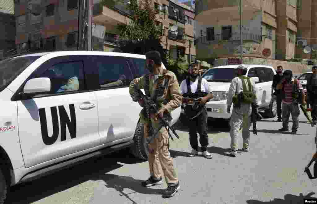 Free Syrian Army fighters carry their weapons as they escort U.N. vehicles carrying chemical weapons experts at the site of an alleged chemical weapons attack in a Damascus suburb, August 28, 2013.