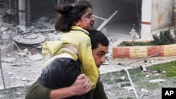 Syrian man carries his sister who was wounded in a government airstrike hit the neighborhood of Ansari, in Aleppo, Syria, Sunday, Feb. 3, 2013.
