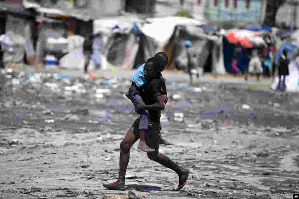 A youth carries a boy to get help, after the boy was overcome by tear gas fired by police outside Parliament where lawmakers are debating whether or not to start impeachment proceedings for Haitian President Jovenel Moise in Port-au-Prince, Aug. 21, 2019.