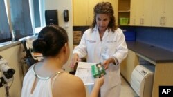 FILE- Nurse practitioner Juliana Duque gives a patient who is pregnant insecticide and and information about mosquito protection at the Borinquen Medical Center in Miami, Aug. 2, 2016.