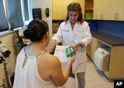 FILE- Nurse practitioner Juliana Duque works with a patient in Miami. NPs provide much of the same care as doctors, including routine checkups and writing prescriptions.