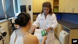 FILE- Nurse practitioner Juliana Duque gives a patient who is pregnant insecticide and and information about mosquito protection at the Borinquen Medical Center in Miami, Aug. 2, 2016.