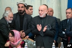 Former Afghan President Hamid Karzai, second from right in the foreground, applauds during the intra-Afghan talks in Moscow, Feb. 6, 2019.